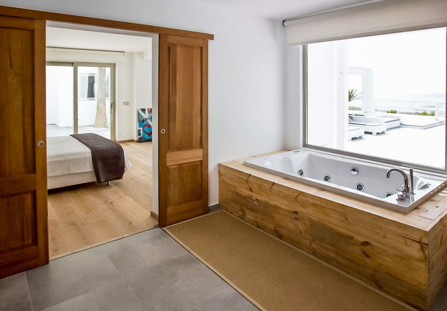 Timber-boxed bathtub beside a sliding door to the bedroom at Between Pines, Ibiza