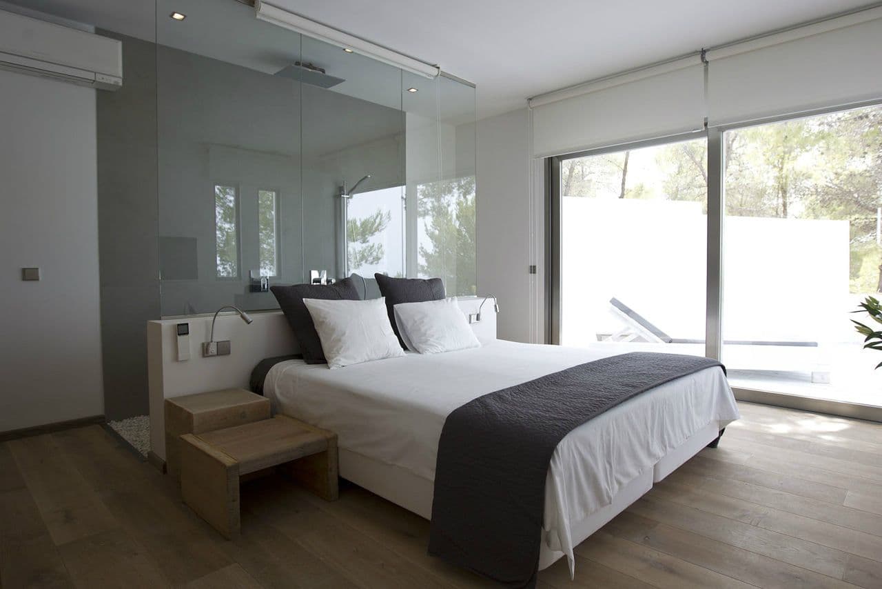 Bedroom suite with a glass-walled en-suite and garden views at Between Pines, Ibiza