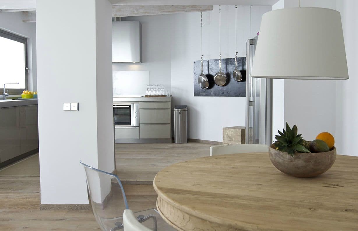 Round oak breakfast table beside the kitchen under a drum pendant at Between Pines, Ibiza