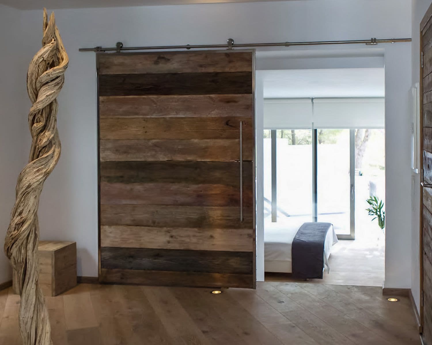 Dressing area with a reclaimed-wood sliding door and driftwood sculpture at Between Pines, Ibiza