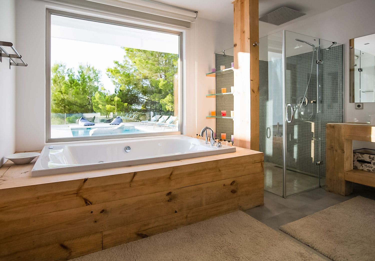 En-suite with a timber-clad tub and walk-in shower framing a pool view at Between Pines, Ibiza
