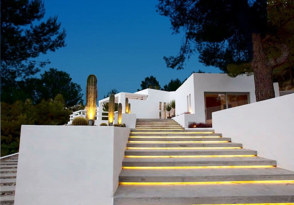 Lit entrance steps and cacti leading to the white villa at dusk at Between Pines, Ibiza