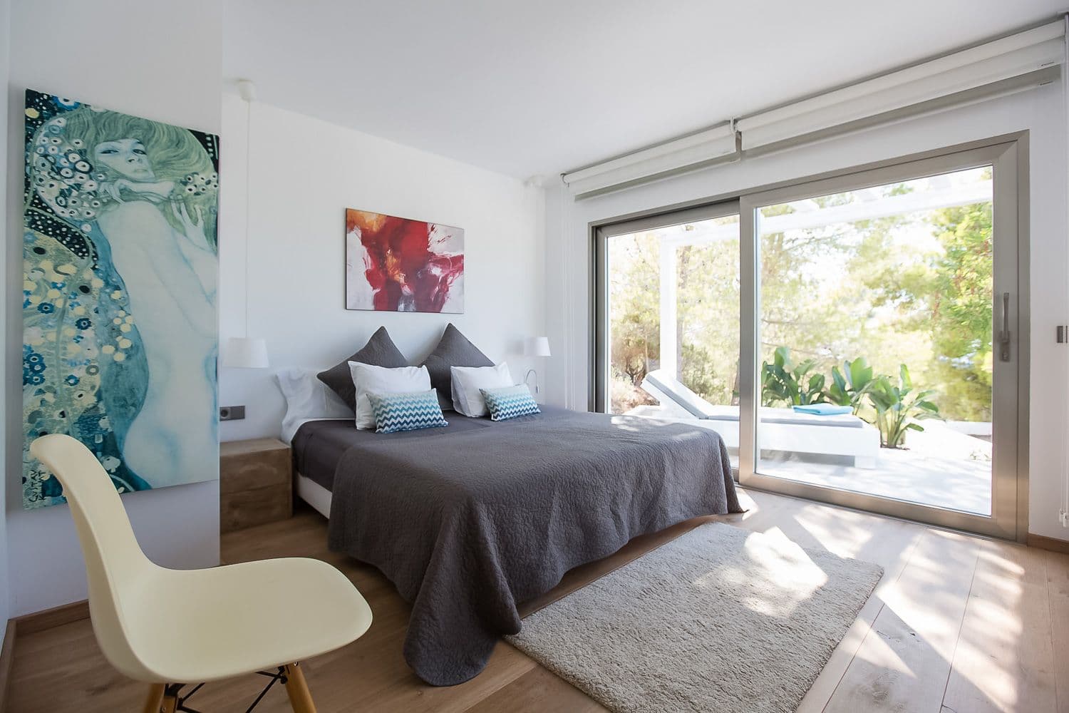 Master bedroom with terrace doors to the pool and a large Klimt-style canvas at Between Pines, Ibiza