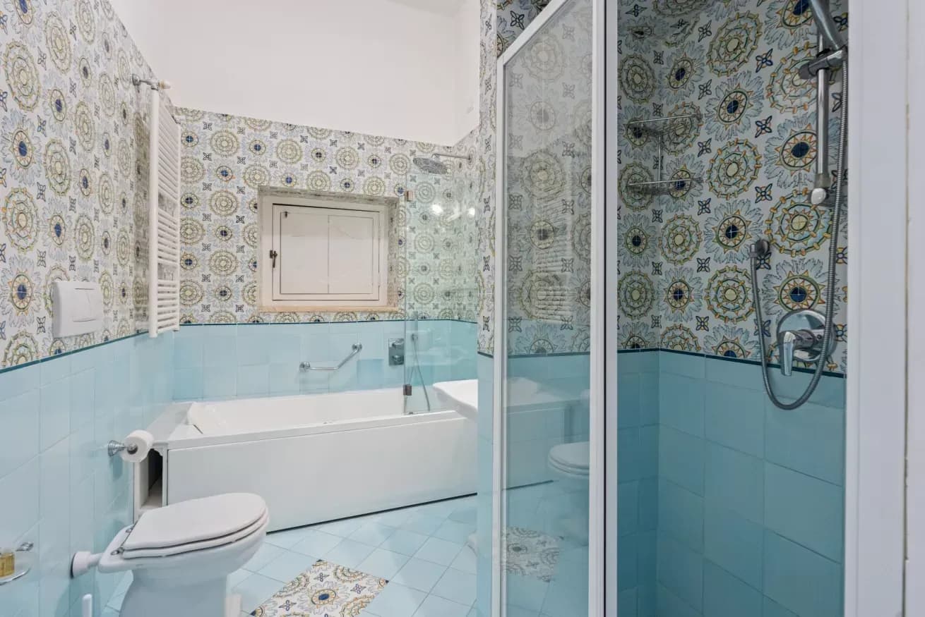 Bathroom with patterned blue tiling and a bathtub