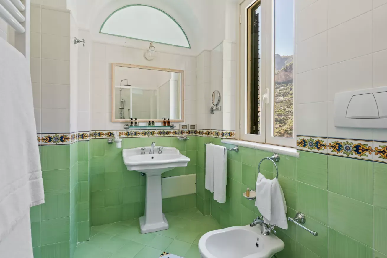 Bathroom with green tiling, pedestal sink and bidet