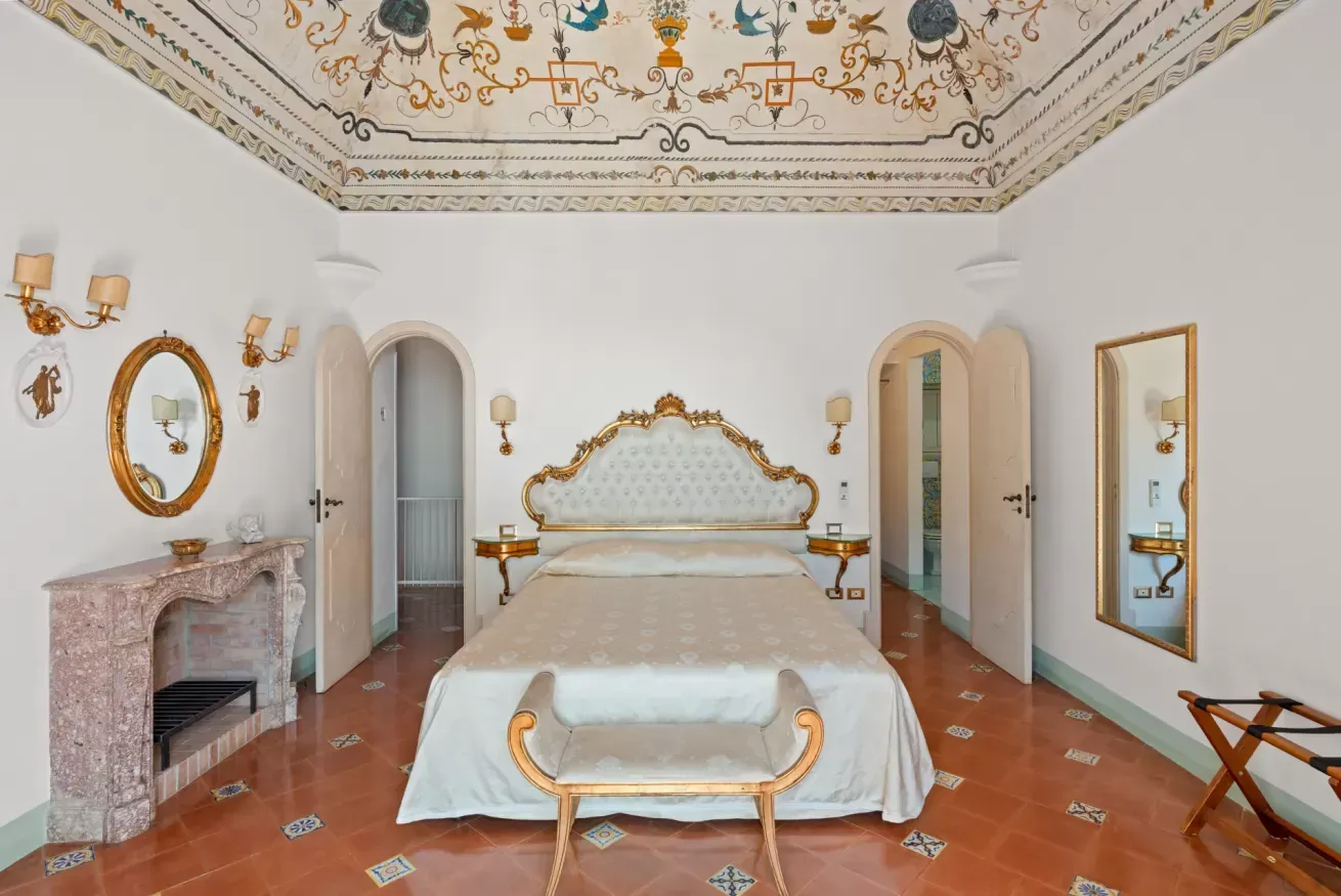 Bedroom with a painted ceiling, ornate bed and arched doorways