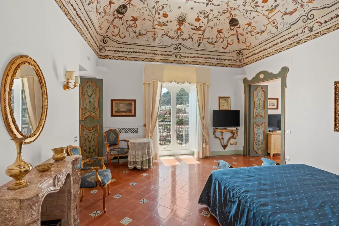 Bedroom with a gilded oval mirror and a window onto the sea