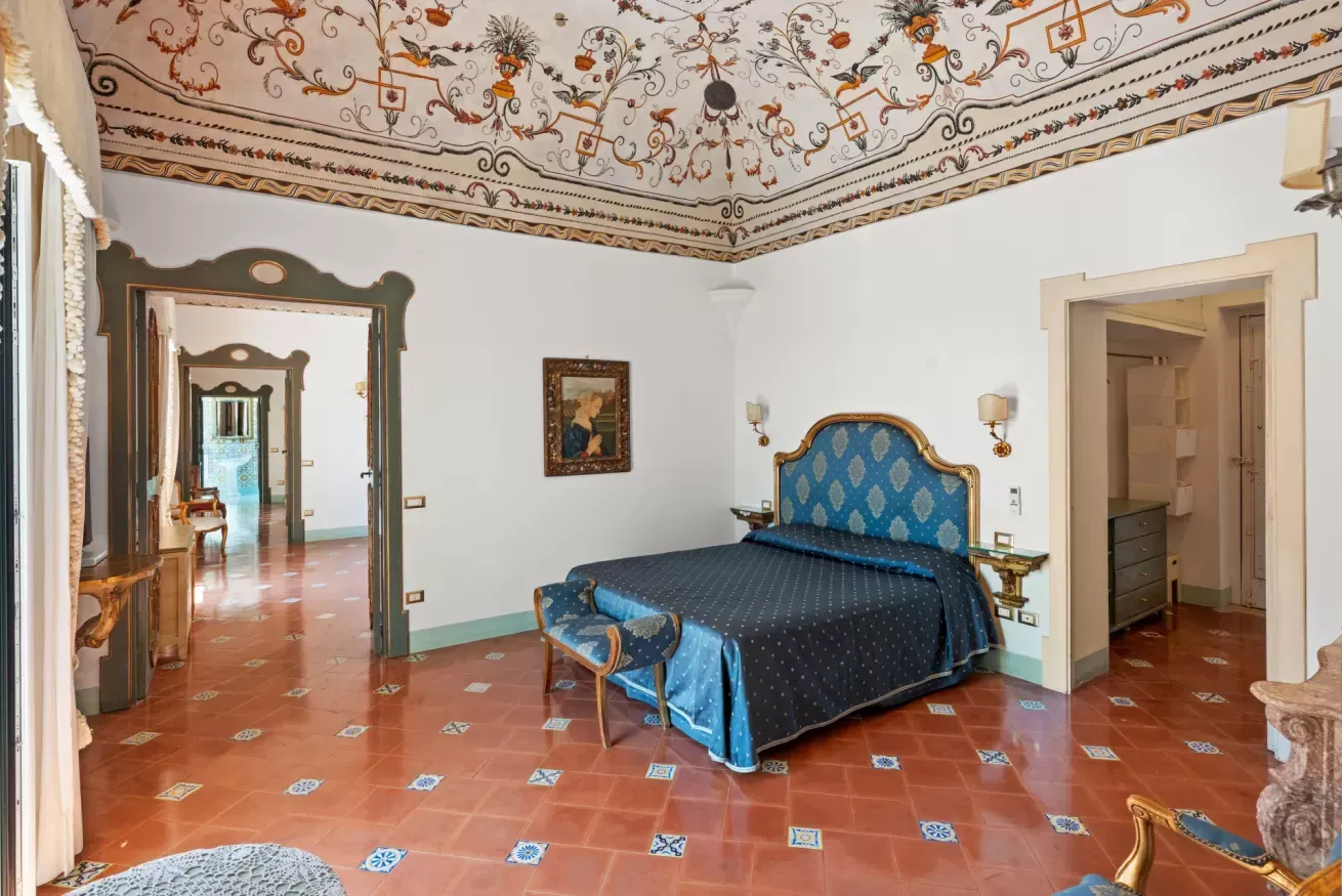 Bedroom with an ornate mirror and elaborately painted ceiling