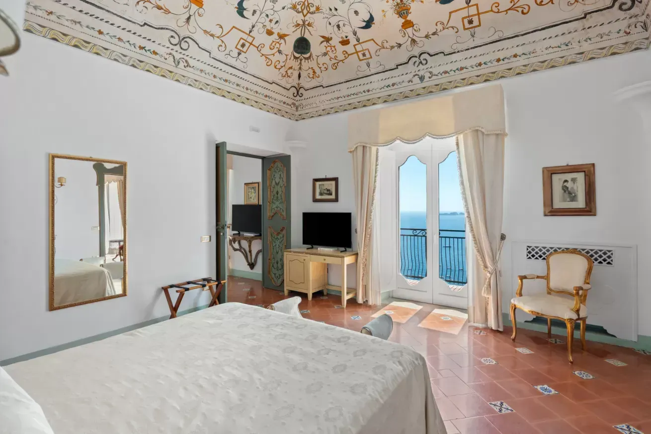 Twin bedroom with a frescoed ceiling and glass doors onto a sea view