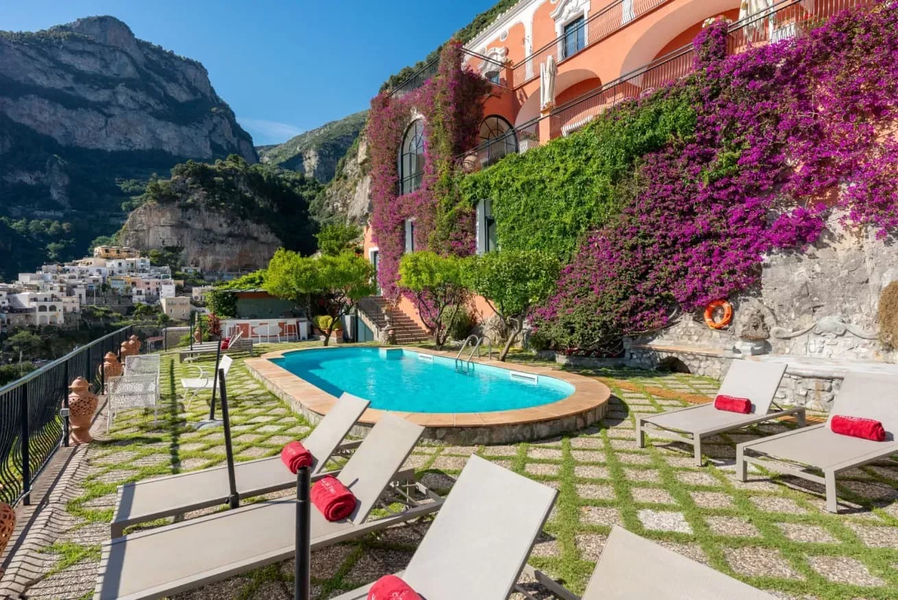 Pool terrace with white sun loungers against the terracotta facade
