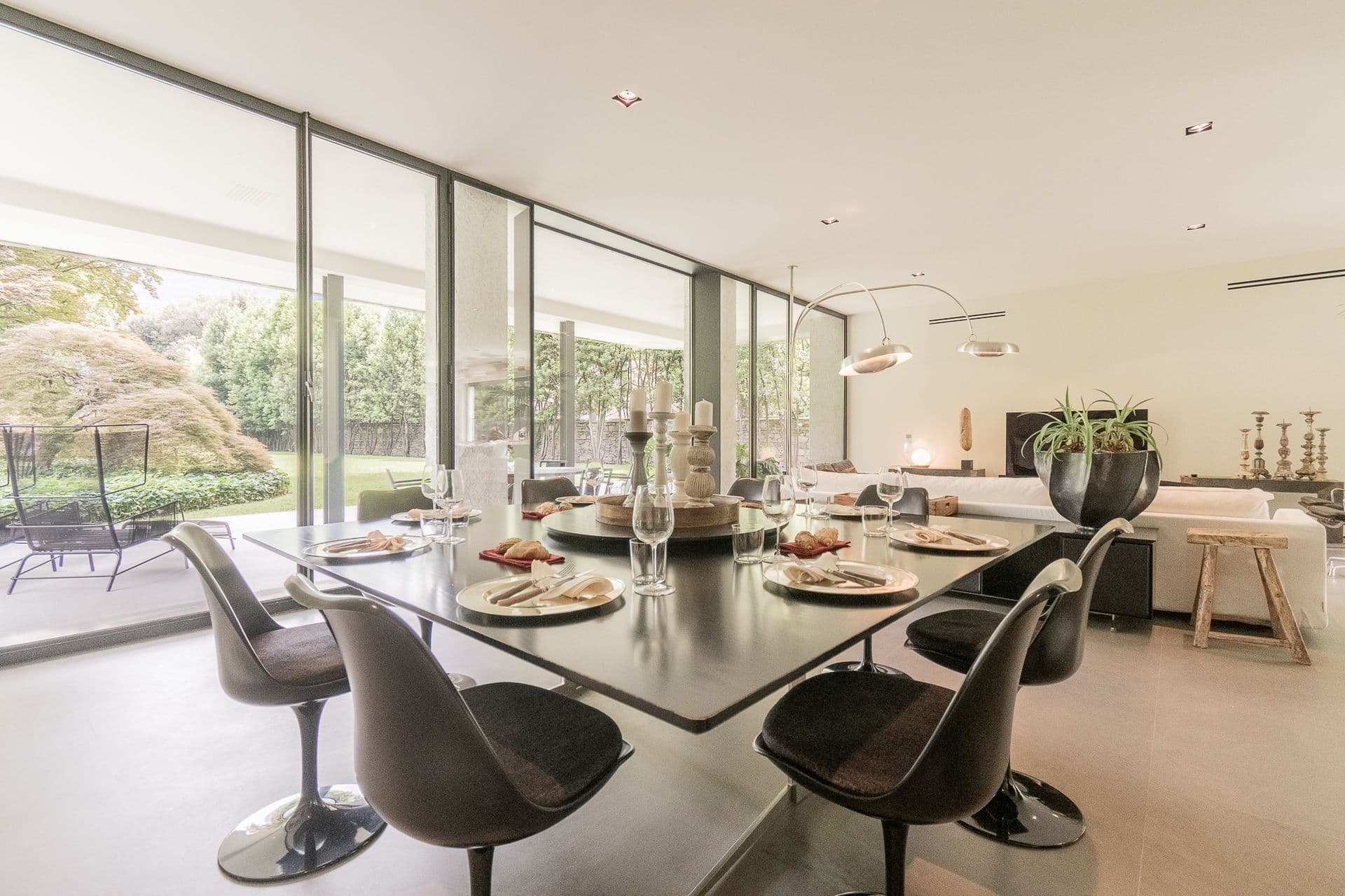 Glass dining table with tulip chairs by a garden-facing glass wall at Elegant Lake Manor, Cernobbio