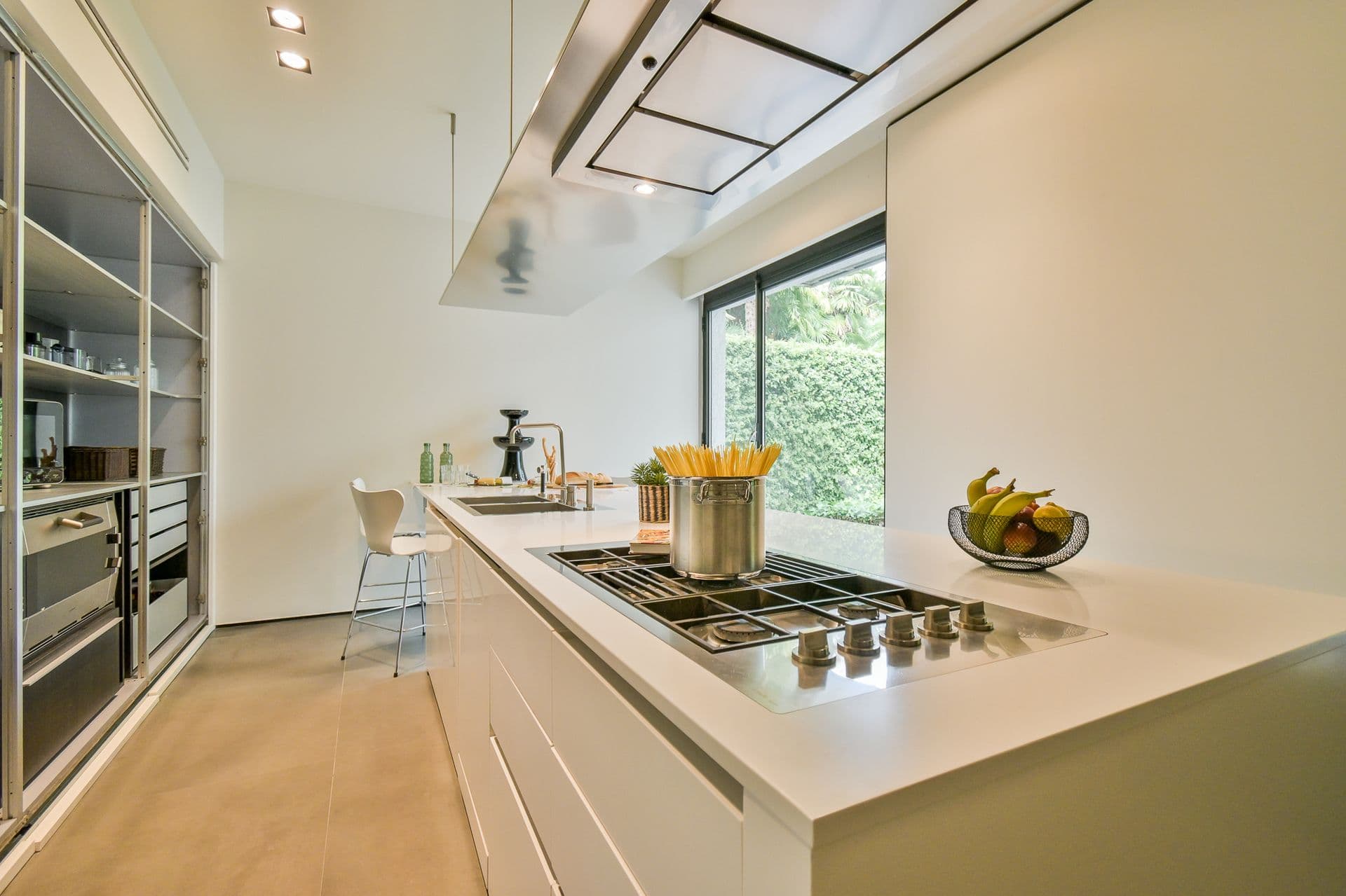 White kitchen with an island gas hob and a garden window at Elegant Lake Manor, Cernobbio
