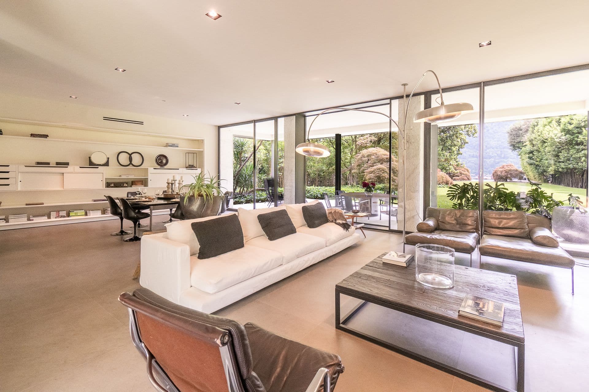 Living room with a white sofa and full glass wall onto the garden at Elegant Lake Manor, Cernobbio