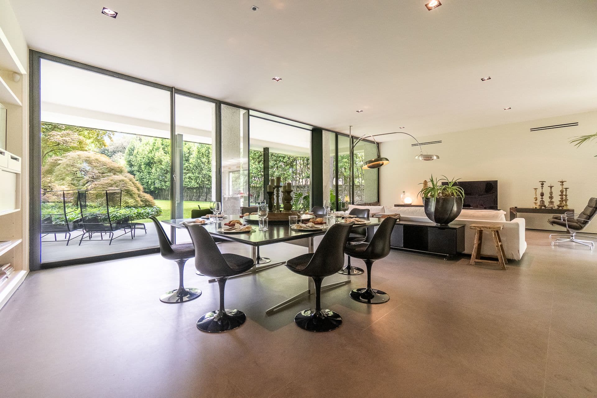 Open-plan living and dining space wrapped in glass onto the garden at Elegant Lake Manor, Cernobbio