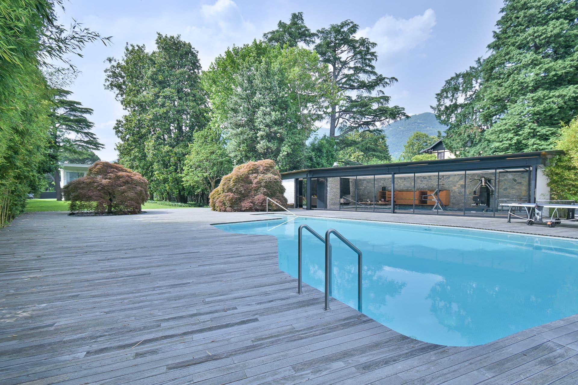 Pool and timber deck set in mature parkland at Elegant Lake Manor, Cernobbio, Lake Como