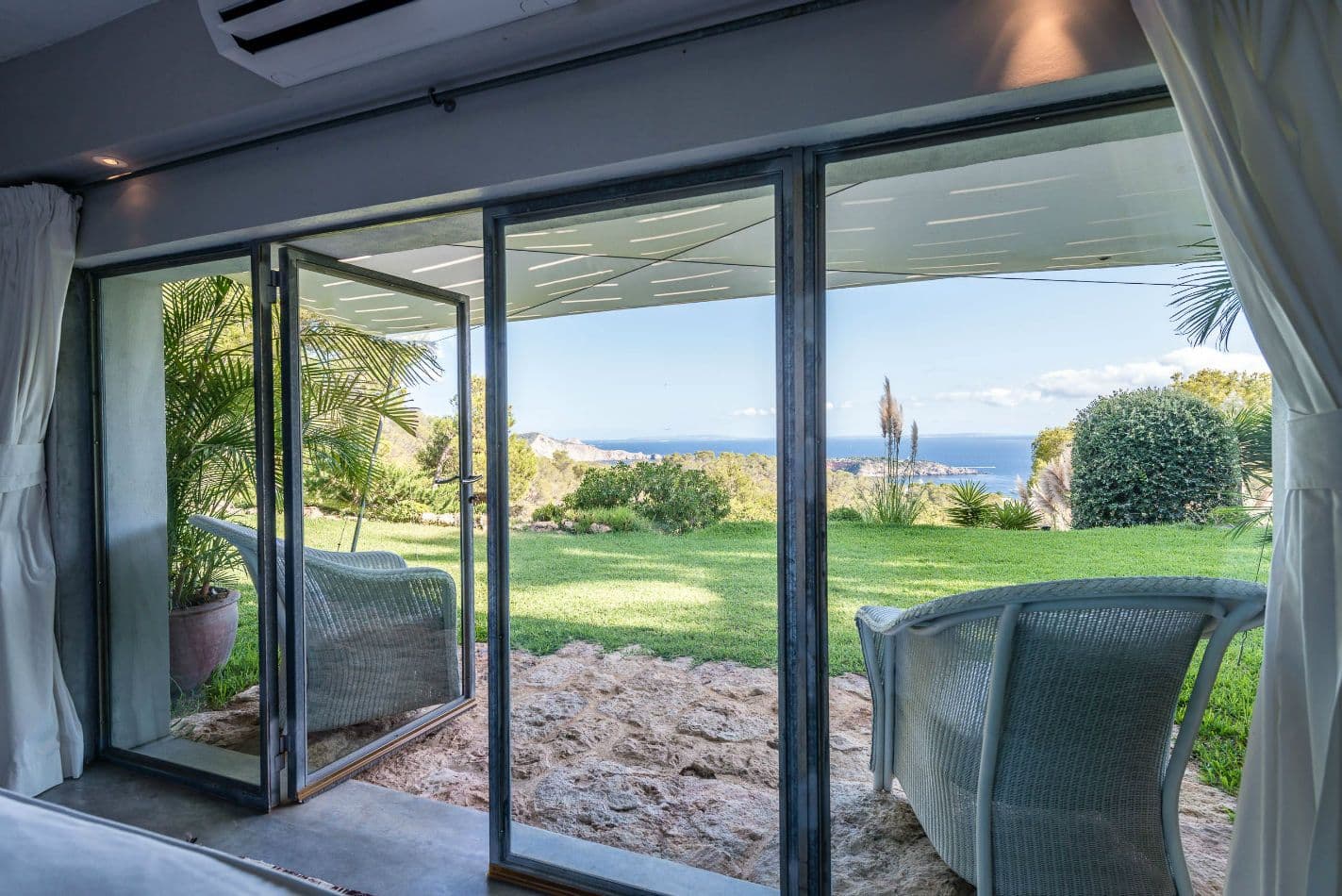 Bedroom with full-height glass doors opening directly onto the garden terrace