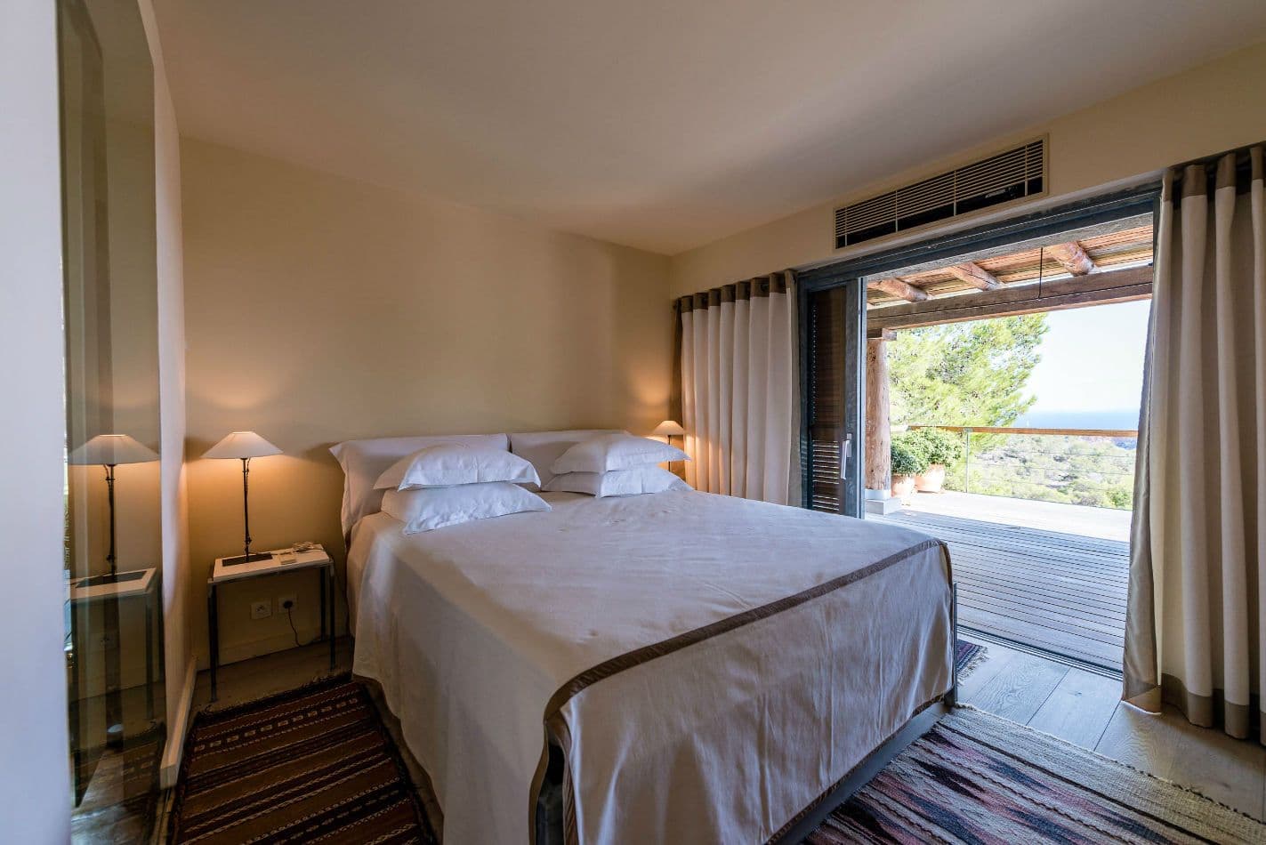Bedroom with neutral linens and sliding doors opening onto the garden
