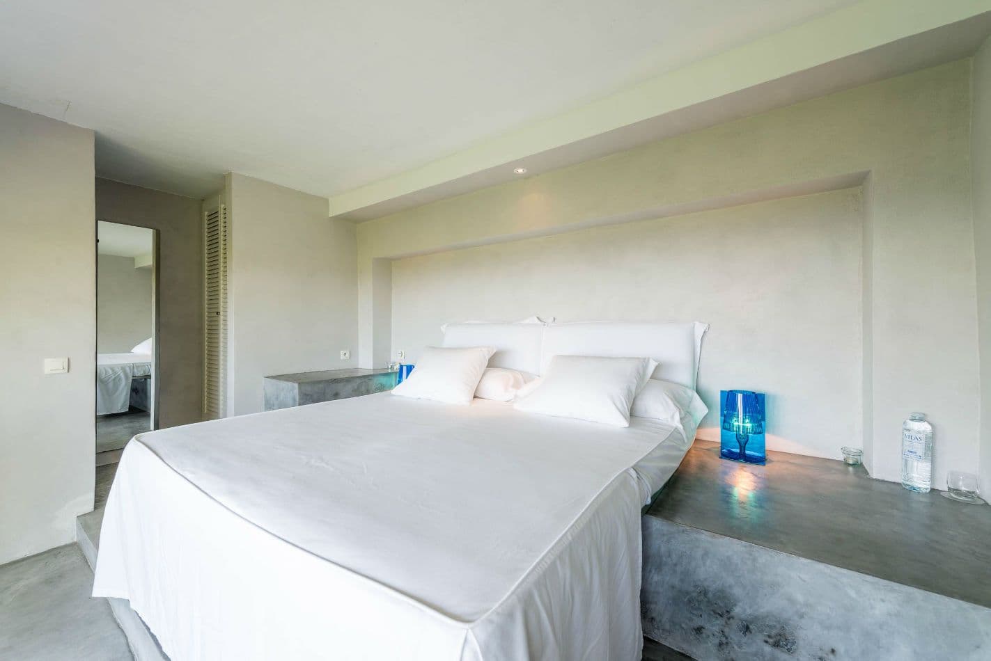Minimalist white bedroom with a sculptural floor lamp