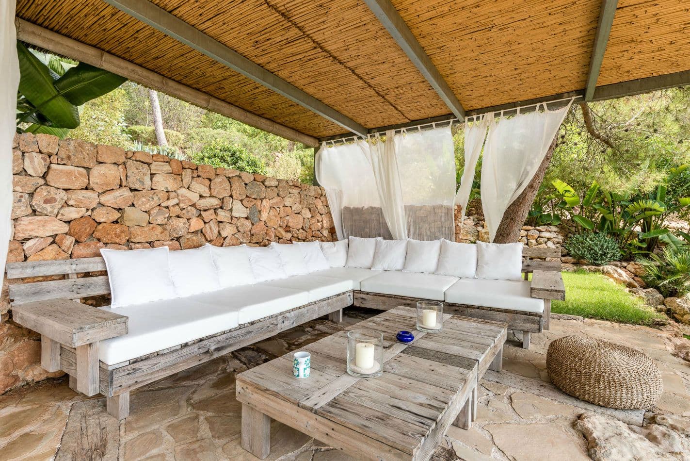 Bohemian outdoor lounge with white cushioned daybeds beneath a woven canopy