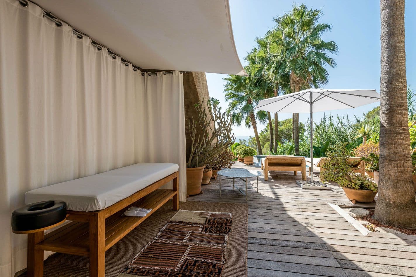 Shaded daybed terrace with white linen drapes and palm tree views