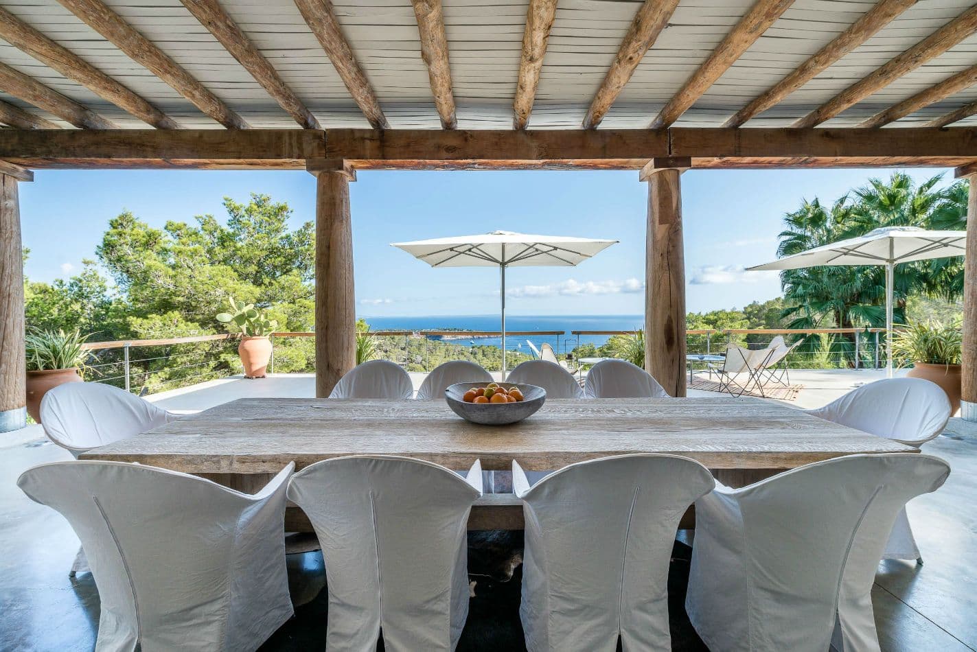 Rustic wooden dining table for eight beneath a beamed terrace with sea views