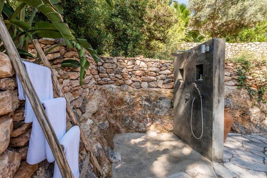 Outdoor stone shower set into a dry stone wall with fresh towels