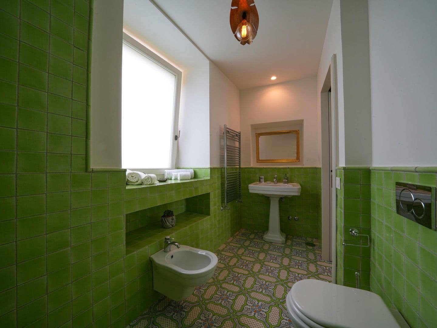 Bathroom lined in green tiles with a pedestal basin at Casarlano Sunsets, Sorrento