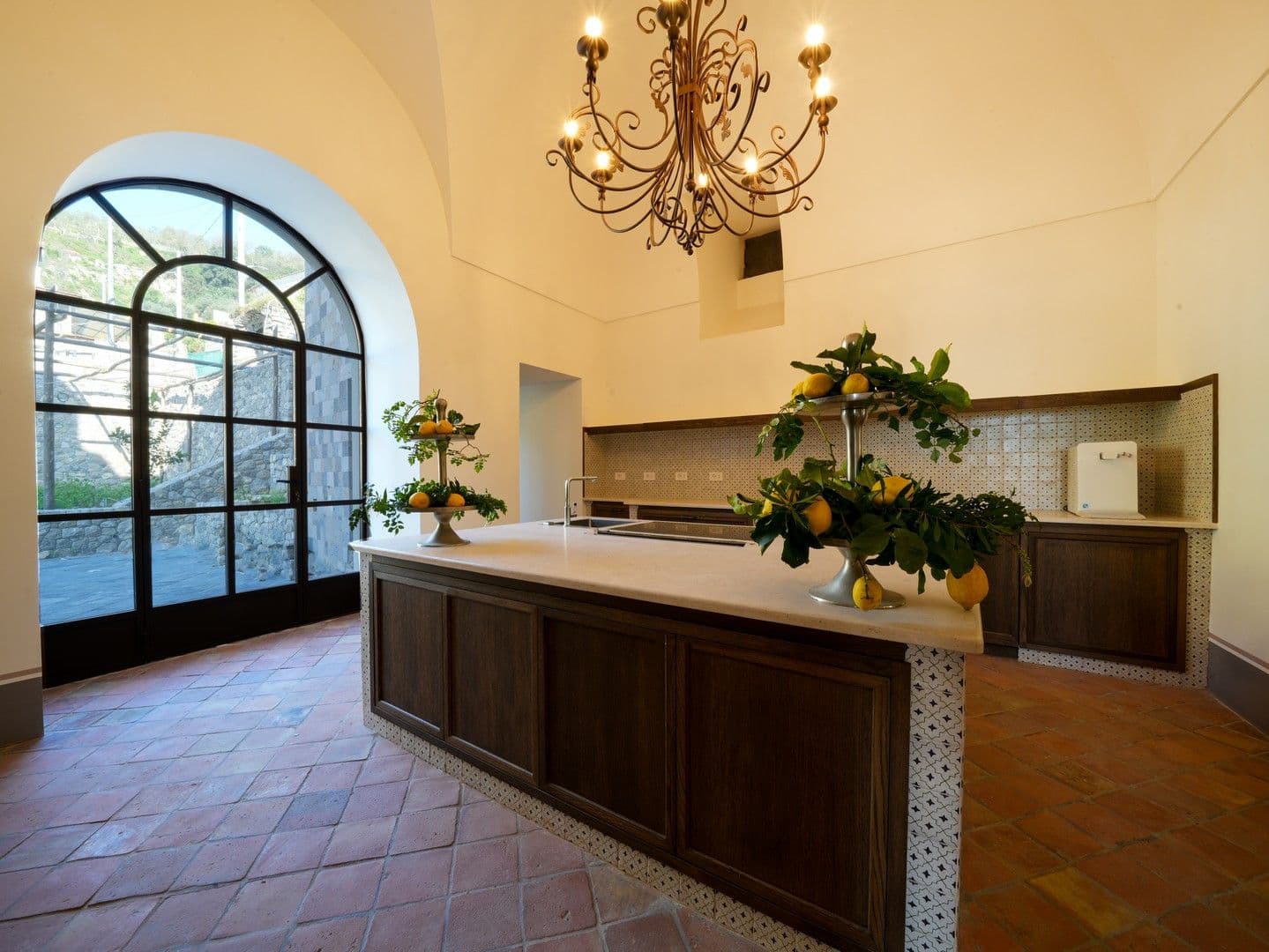 Vaulted kitchen with a timber island and an arched window at Casarlano Sunsets, Sorrento