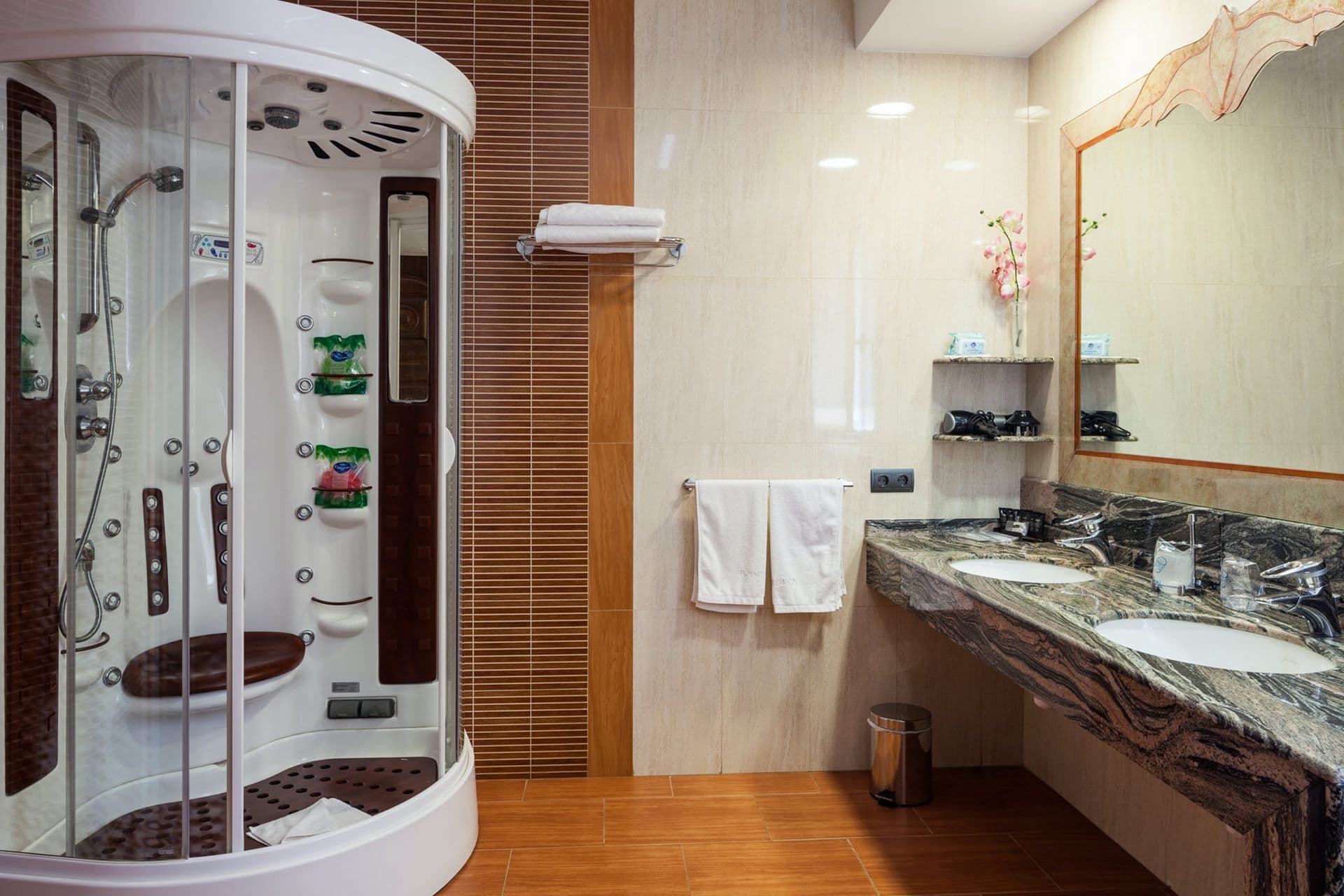 Bathroom with a rounded glass shower pod and marble vanity