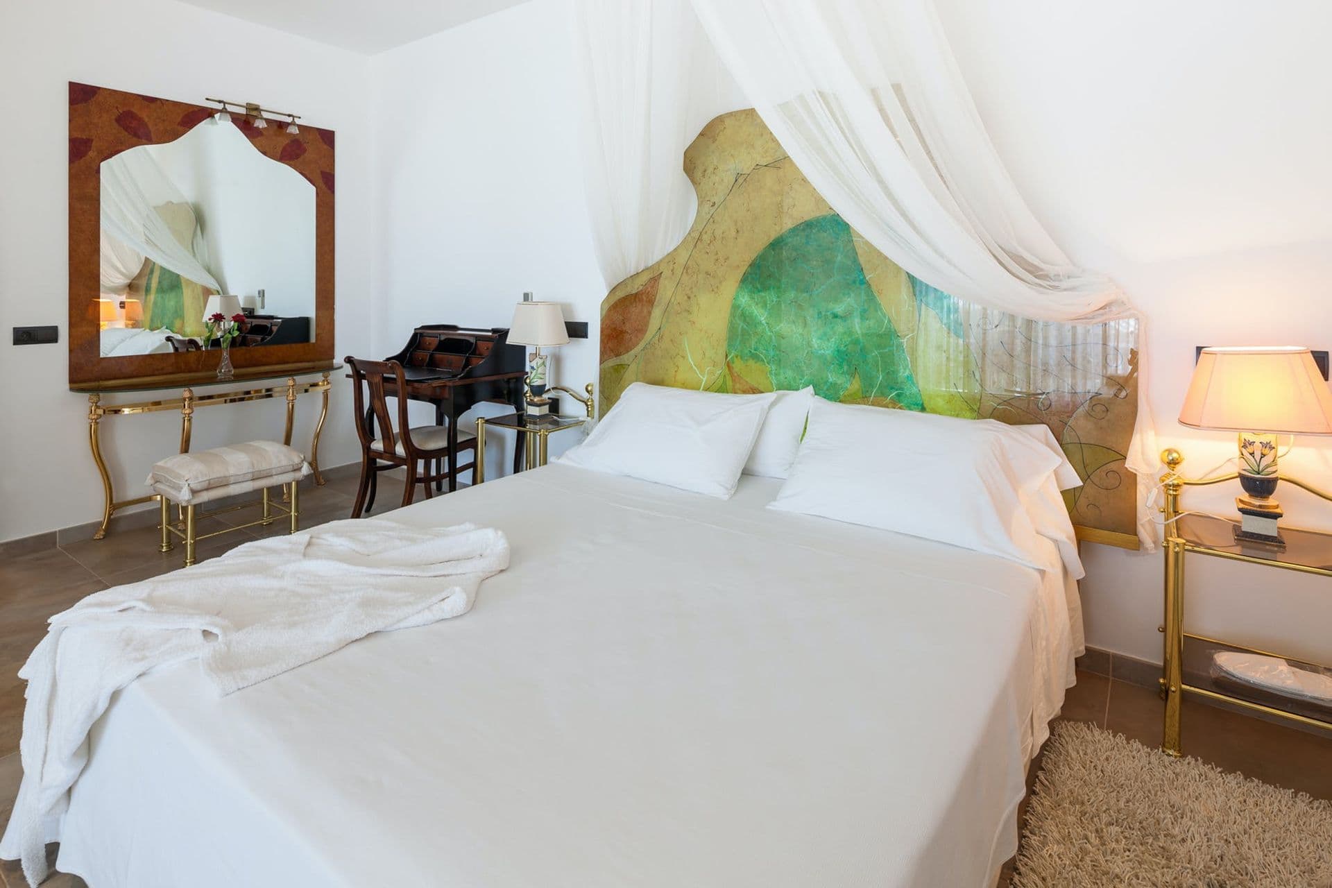 Elegant bedroom with a sheer canopy bed and hand-painted green headboard