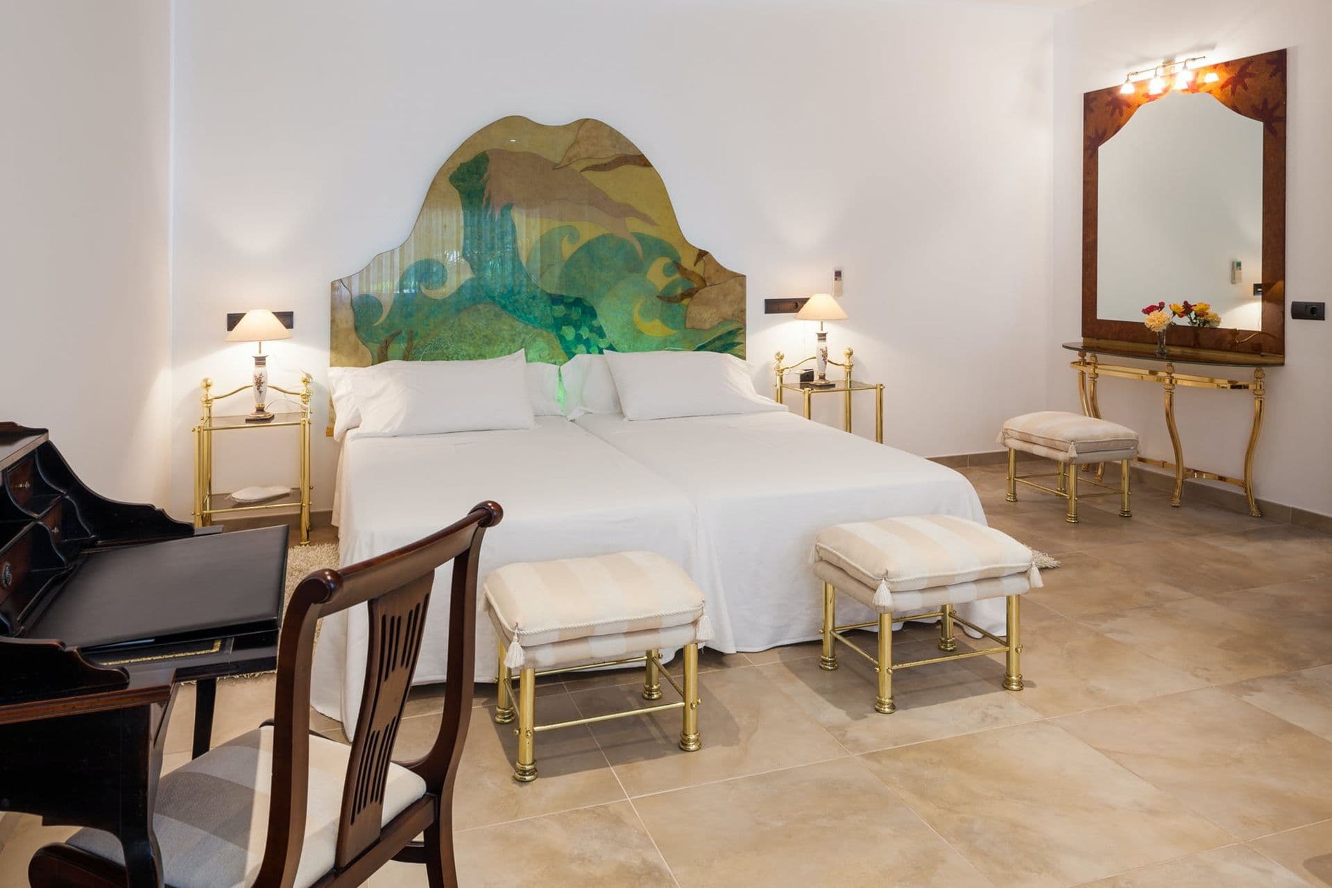 Bedroom suite with an ornate green headboard and adjoining sitting area