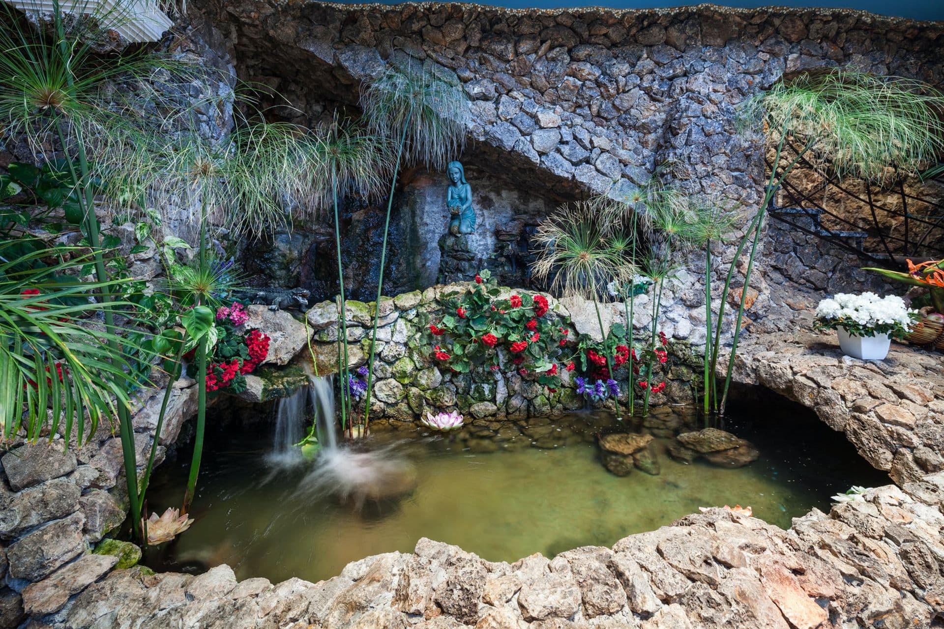 Rockwork grotto with a small waterfall and pond set within the garden