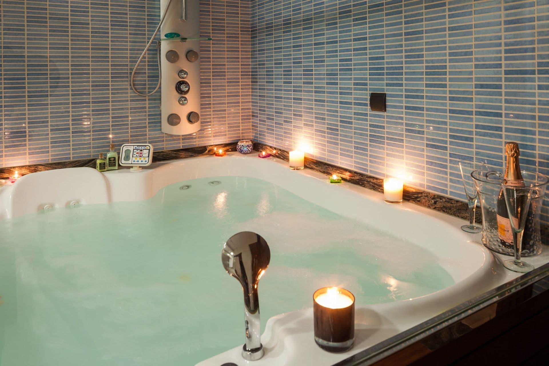 Candlelit indoor jacuzzi tub set within a tiled spa alcove