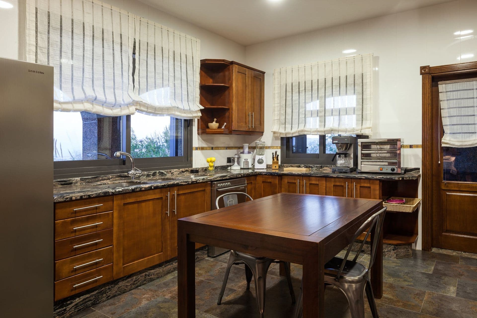 Wooden farmhouse kitchen with a dining table set beside garden doors