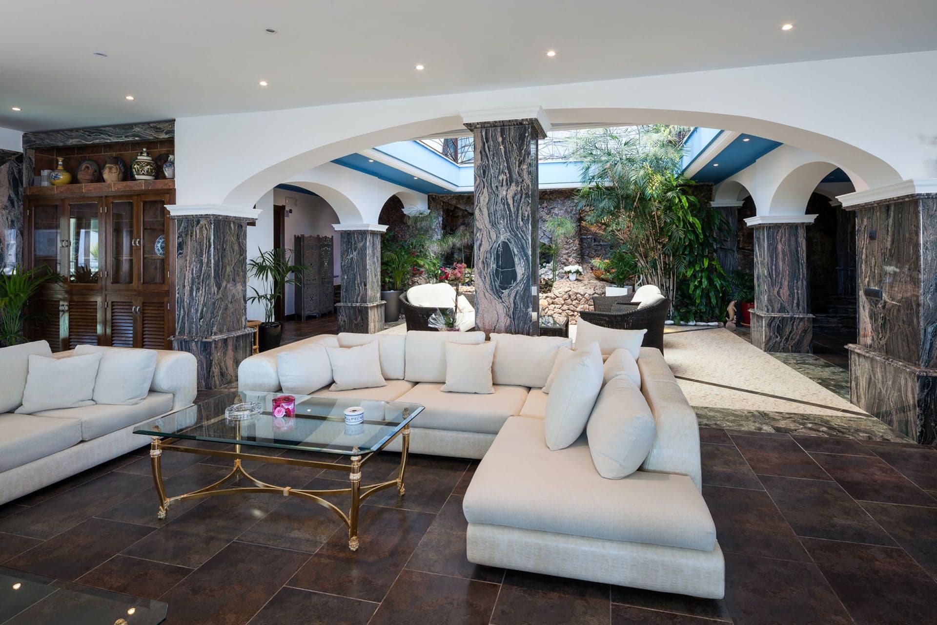 Living area opening onto a marble-columned indoor courtyard atrium