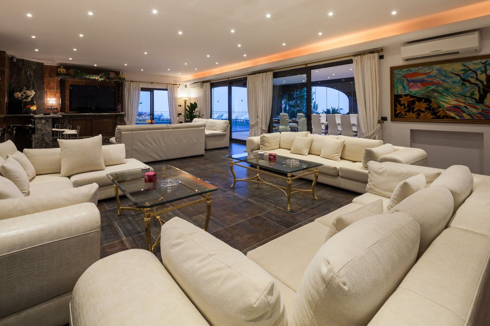 Spacious living room with cream corner sofas and dark stone flooring