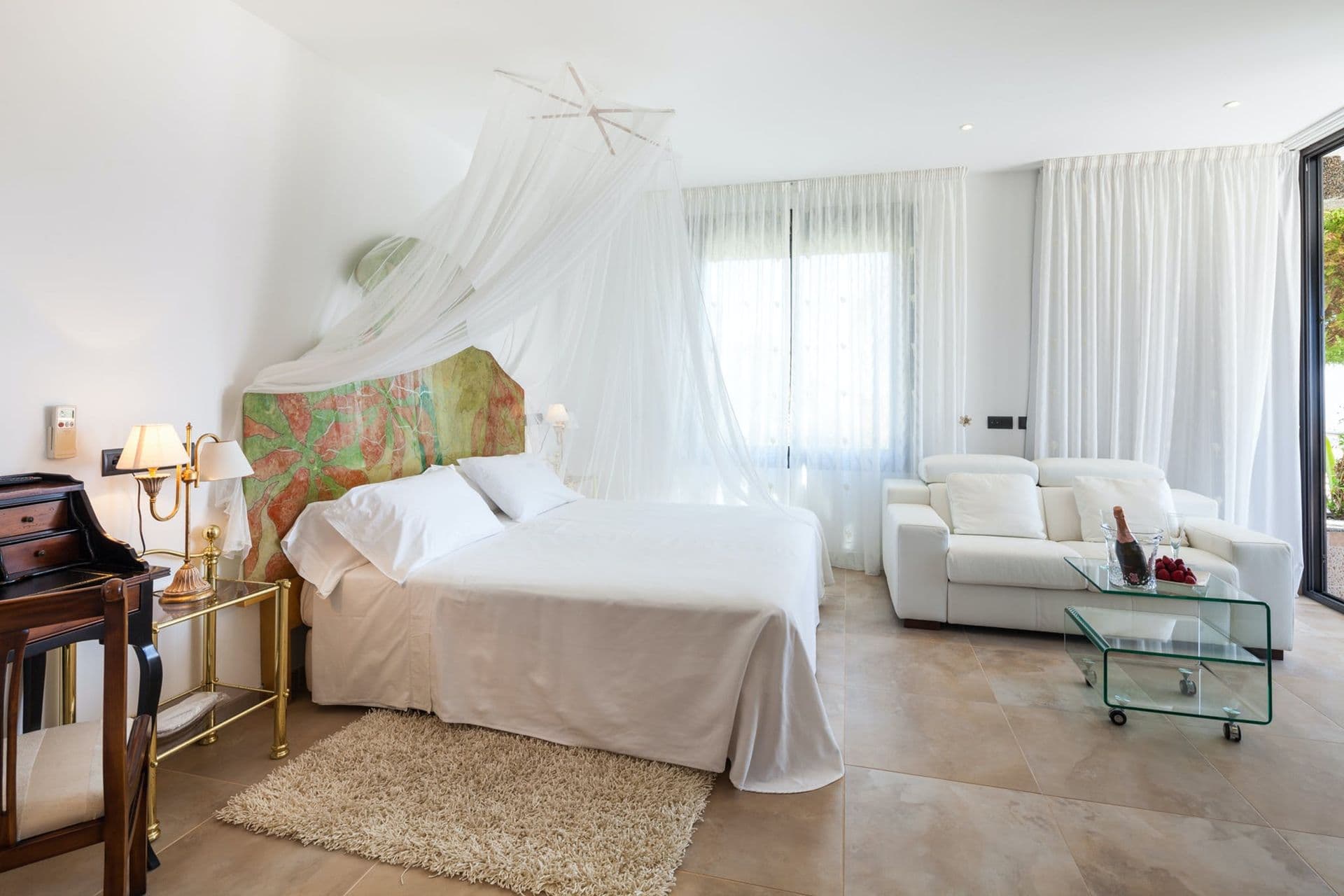 Master bedroom with a canopy bed, mirrored dressing table and gold-trimmed furniture