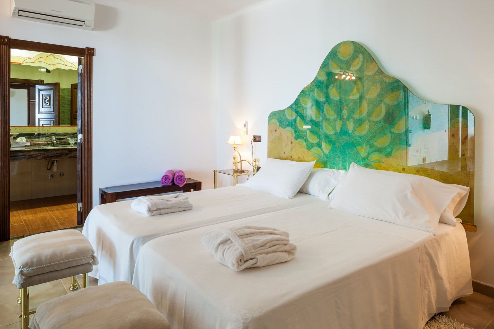 Twin bedroom with matching ornate green headboards and gold-trimmed nightstands