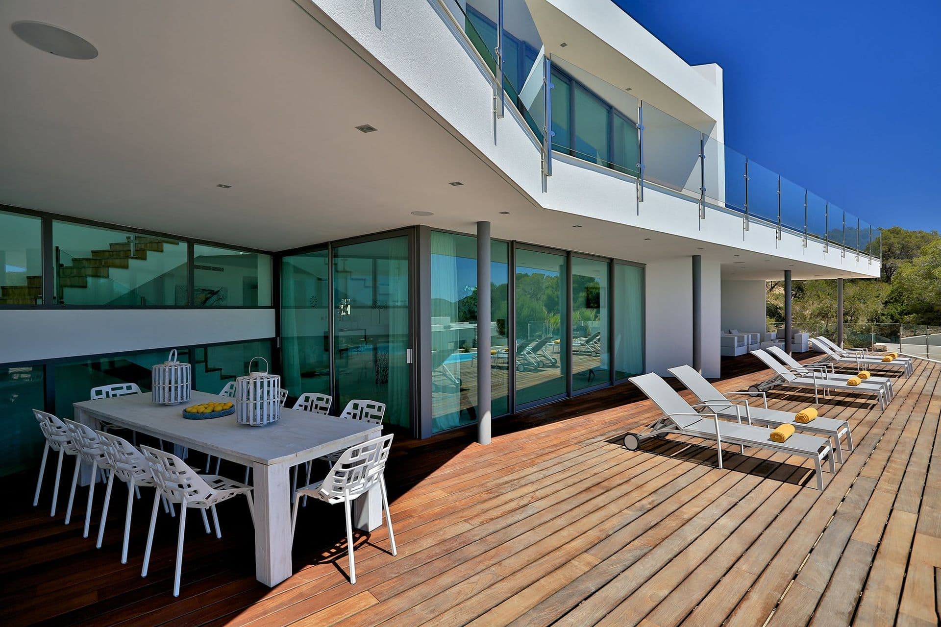 Contemporary white villa with a long timber deck, dining table and sun loungers at Hazy Island View, Ibiza
