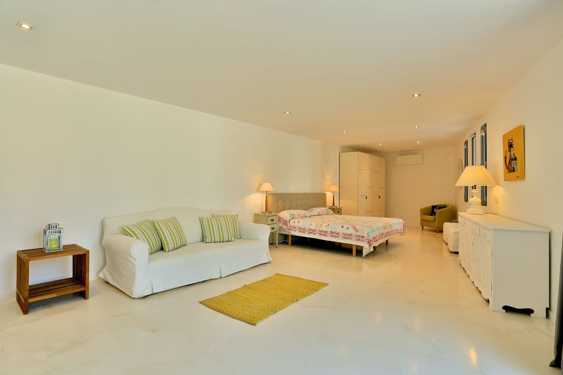 Guest room with a white sofa bed and mustard accent rug at Hazy Island View