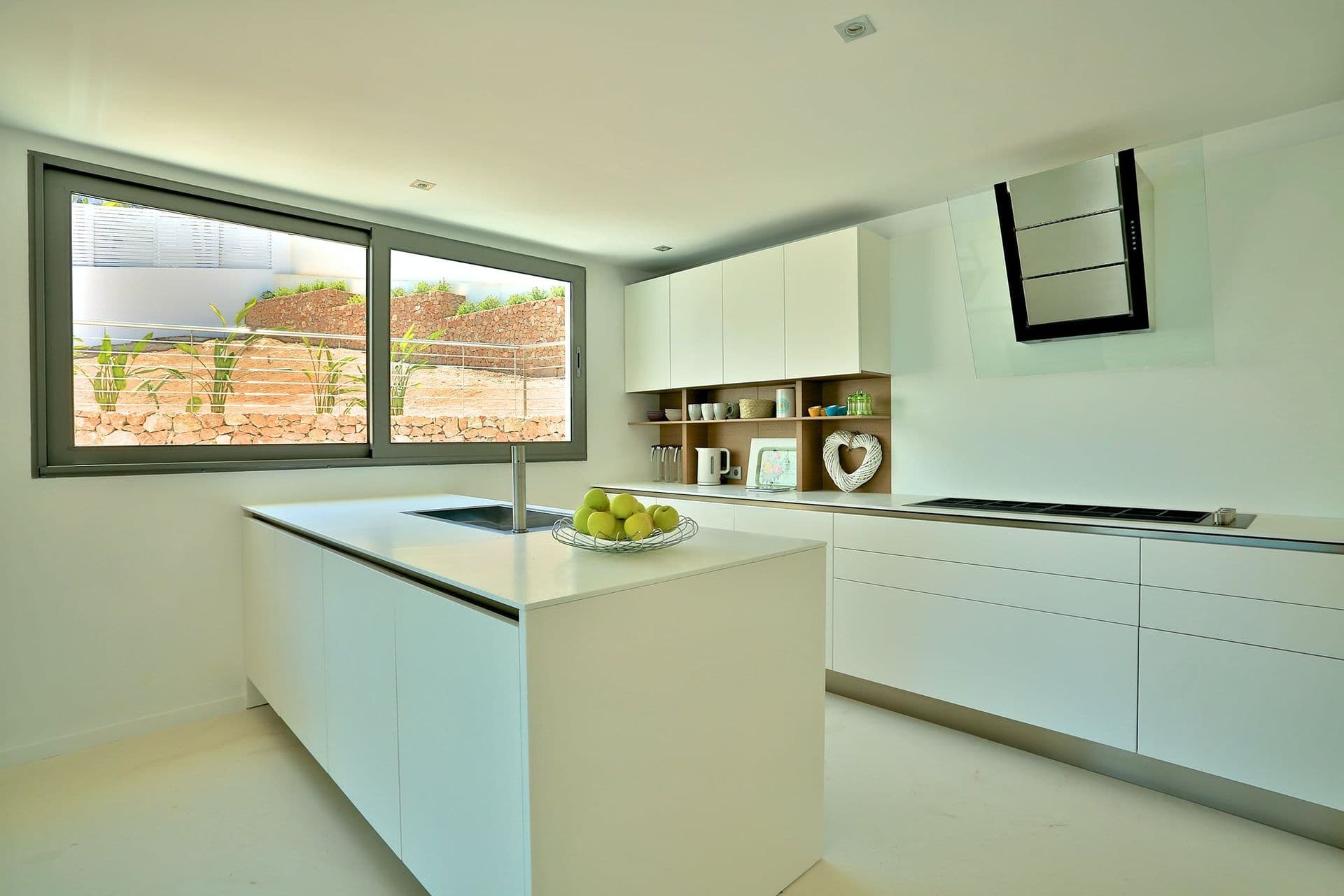 White kitchen with central island and large windows at Hazy Island View