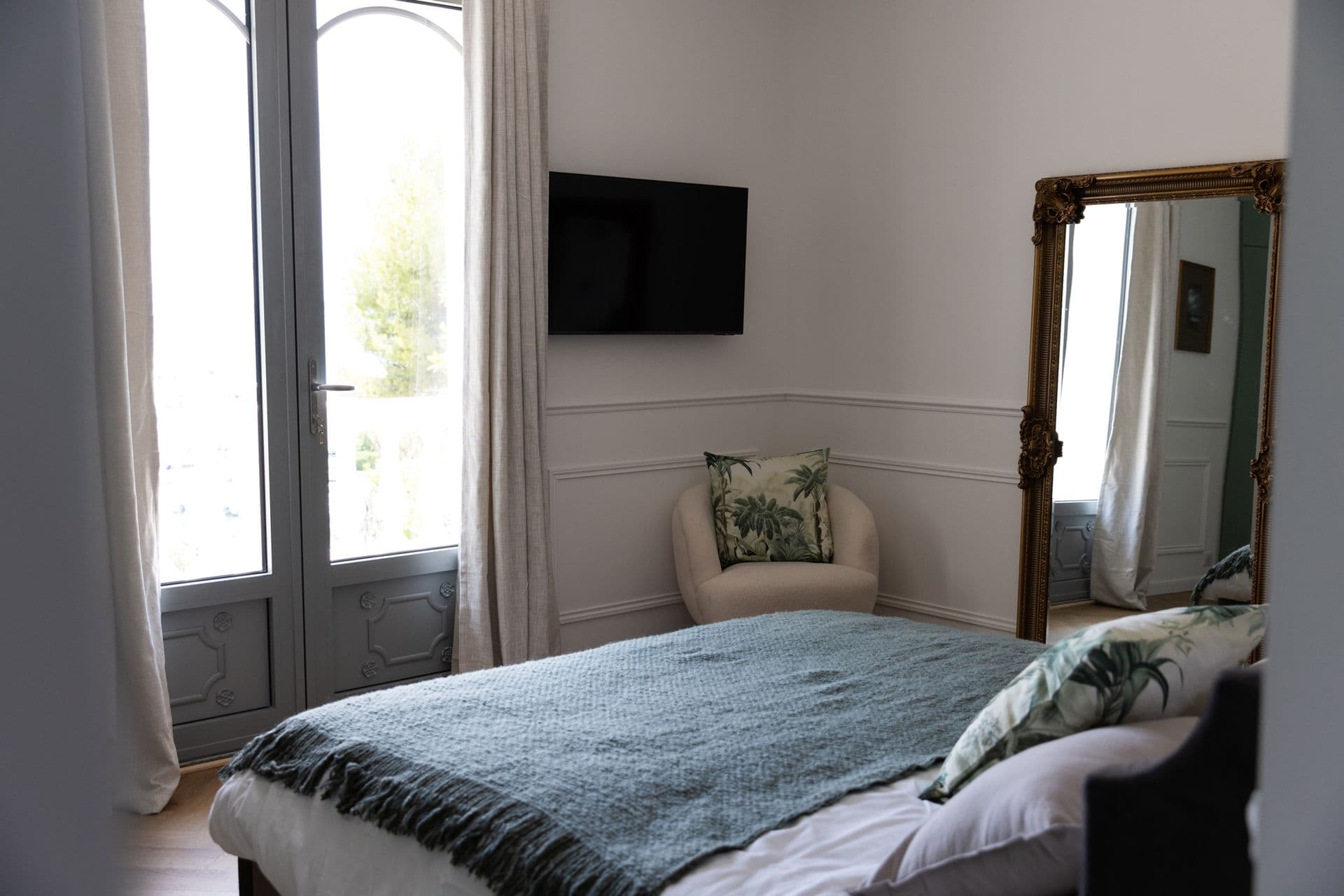 Double bedroom in soft green with a gilt mirror and tall windows at Cote D'Azur Sunshine, Antibes