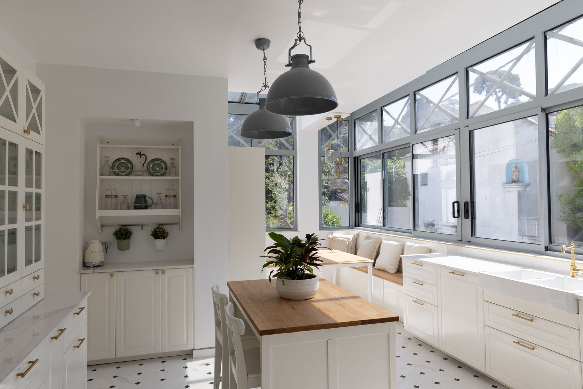 White kitchen with an island and a built-in banquette on patterned tiles at Cote D'Azur Sunshine, Antibes