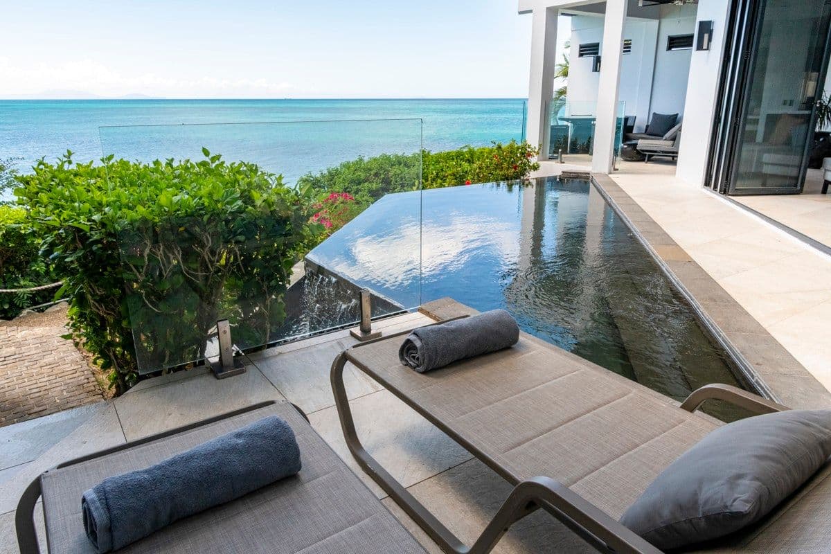 Loungers beside the infinity pool over the sea at Views in the Tropics, Antigua
