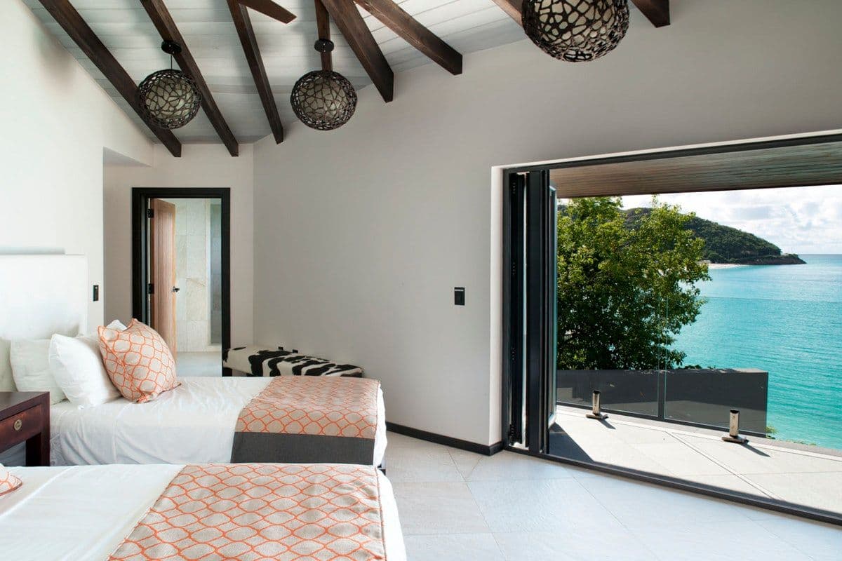 Twin bedroom with sea views under a beamed ceiling at Views in the Tropics, Antigua