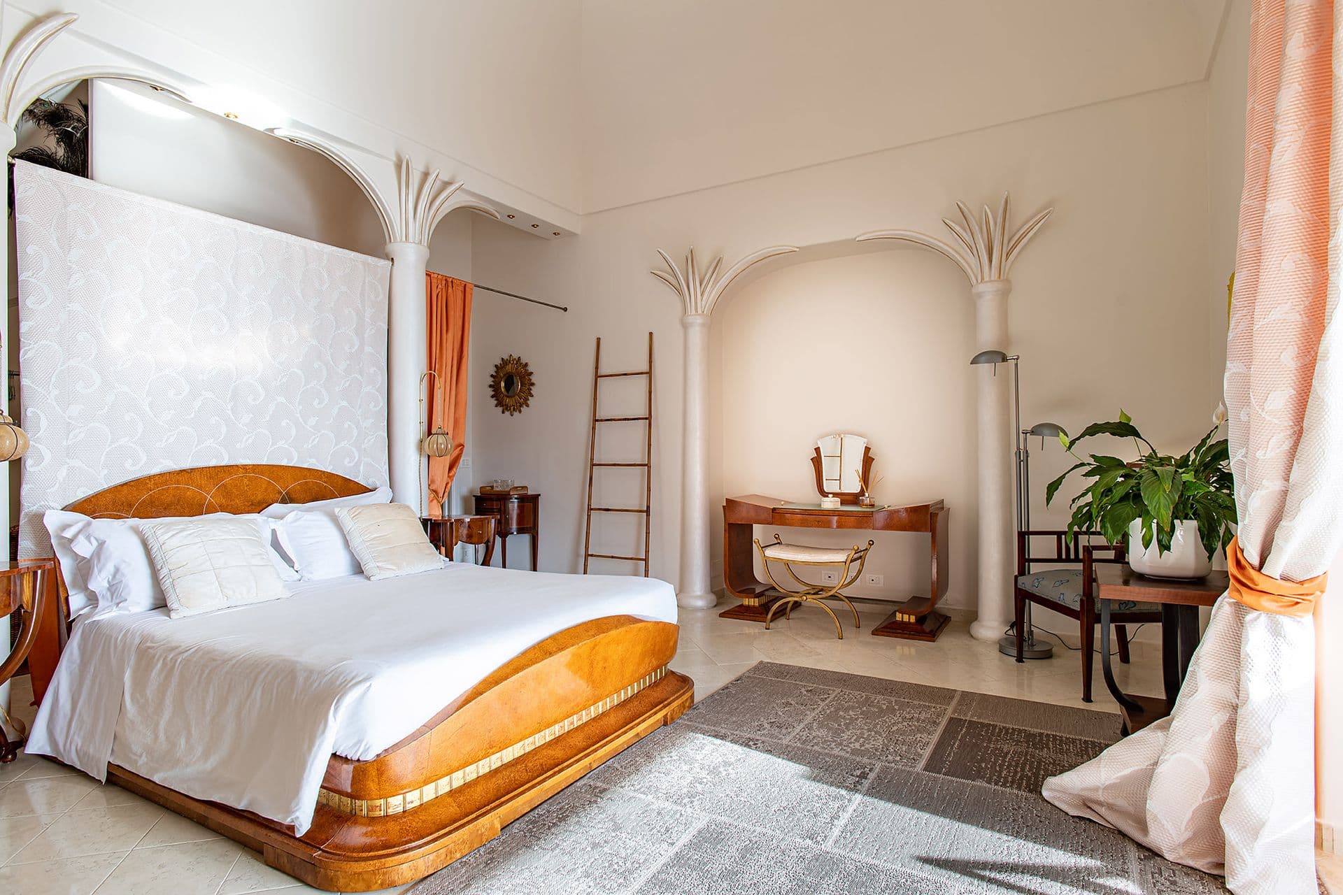 Bedroom with a carved wooden headboard and coral curtains
