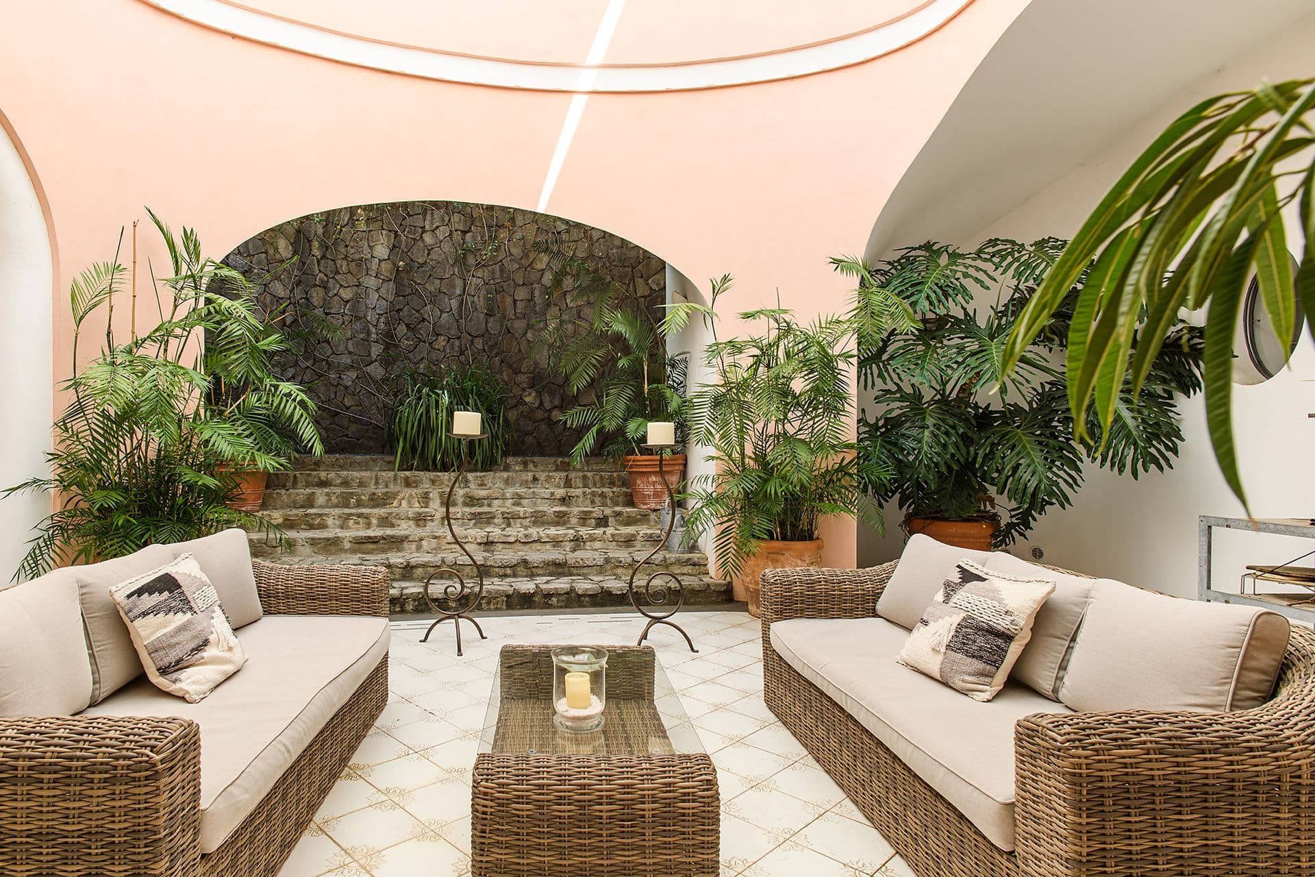 Sheltered courtyard seating area with potted plants and a stone archway