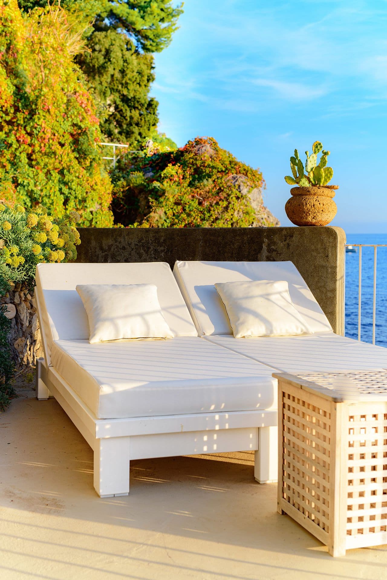 Terrace sun loungers set among greenery with sea views