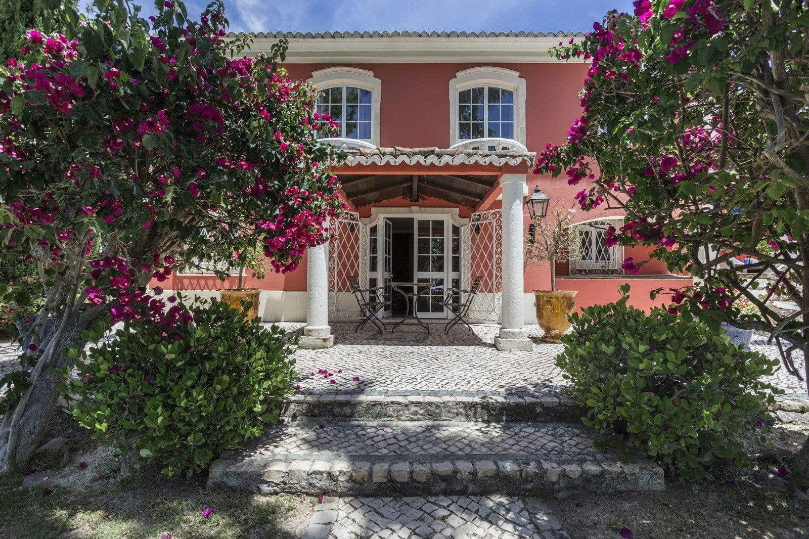 Terracotta villa facade with bougainvillea and columned entrance at Your Algarve Oasis