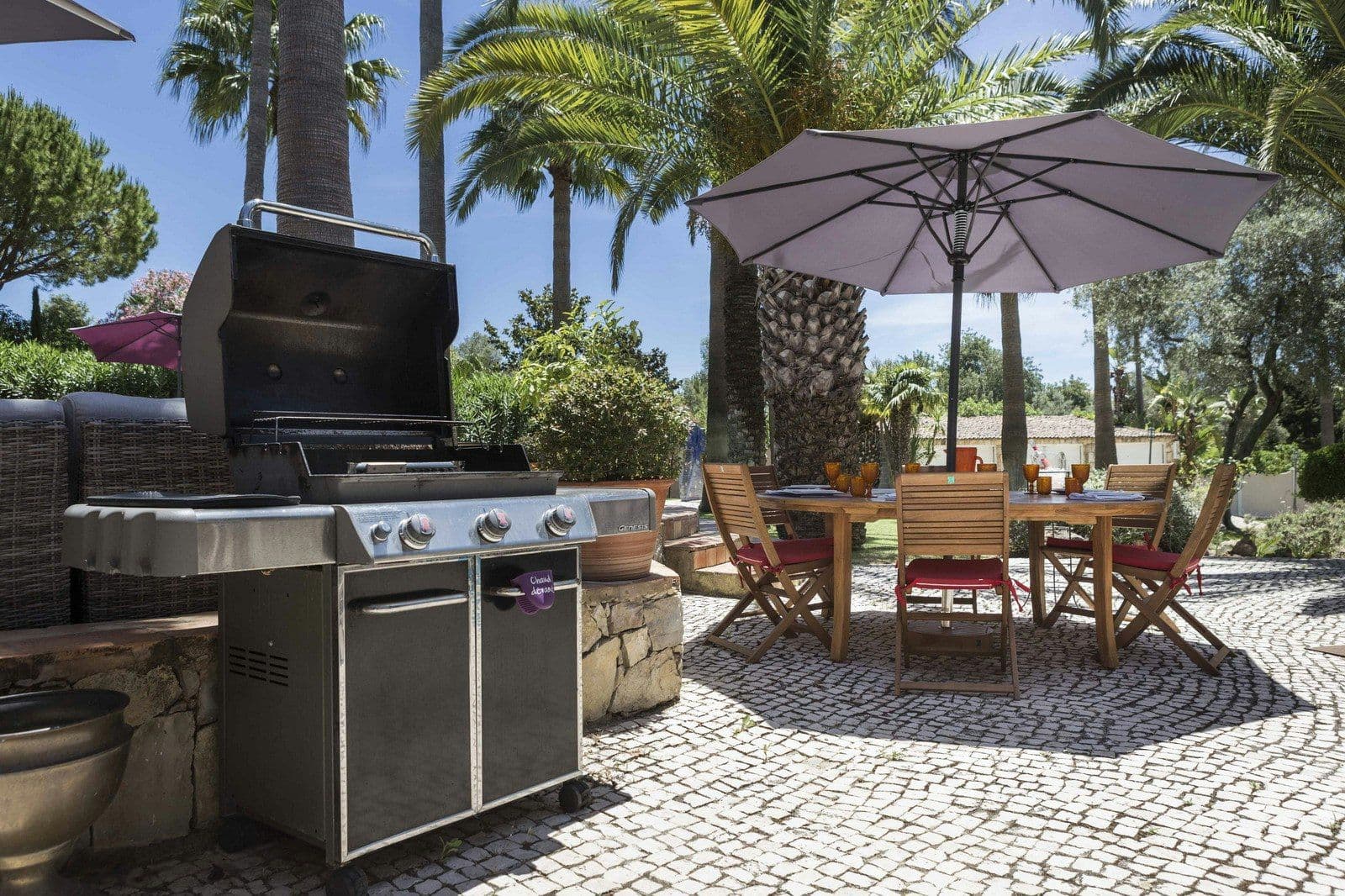 Outdoor kitchen with a gas grill and dining table on the terrace at Your Algarve Oasis